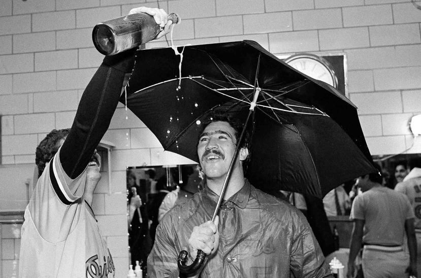 El lanzador Sammy Stewart (derecha) de los Orioles de Baltimore, usa un paraguas mientras su compañero Bill Swaggerty le vierte una bebida tras vencer a los Cerveceros de Milwaukee y llevarse el título de la División Este de la Liga Americana el 25 de sep