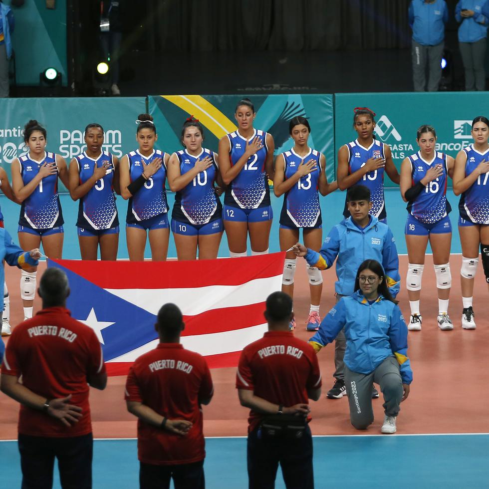 El equipo de voleibol femenino de Puerto Rico escucha los himnos nacionales ante de comenzar su ante Brasil.