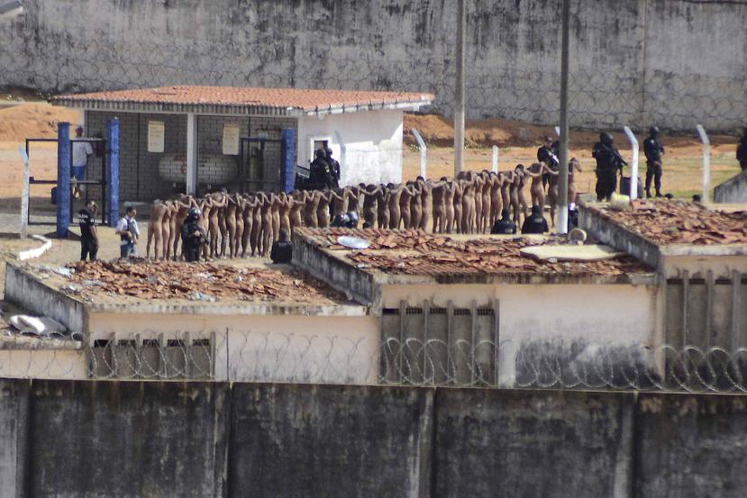 Presos desnudos caminan en fila escortados por la Policía luego de ocurrir un motin en la prisión de Alcaruz.  (AP)