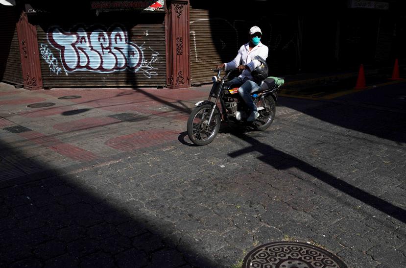 Un hombre con tapabocas pasa en su motocicleta por una calle de la Zona Colonial durante la cuarentena impuesta por el Gobierno para contener la expansión del coronavirus. (Agencia EFE)