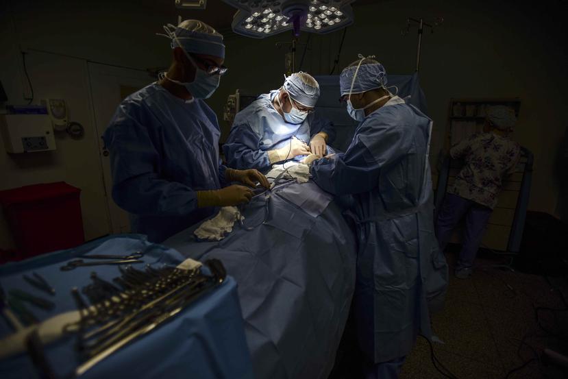 El doctor Reynold López, uno de los pocos cirujanos oncólogos que quedan en Puerto Rico, realiza una operación de tiroides junto a médicos residentes en el hospital Dr. Isaac González Martínez. (AP)