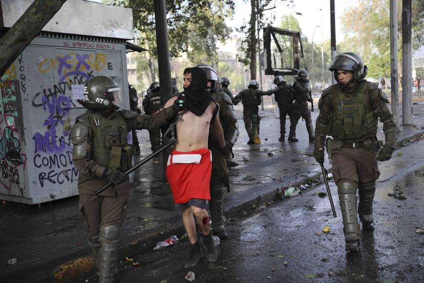 Miembros de la Policía escoltan a un manifestante arrestado durante los disturbios en Chile. (AP / Rodrigo Abd)