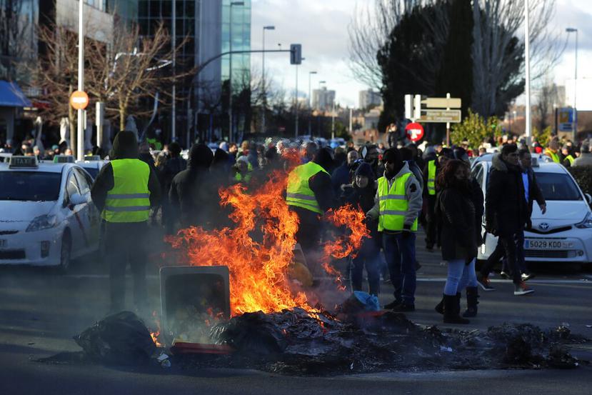 Taxistas queman contenedores de basura para bloquear el acceso a un centro de exposiciones durante una protesta en Madrid, España (AP)