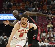 El base de los Bulls de Chicago, Zach LaVine, maneja el balón afuera del pivot del Heat de Miami  Dewayne Dedmon en el encuentro del sábado.