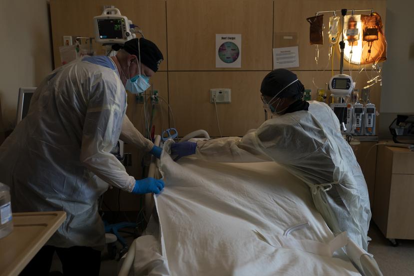 El neumólogo Frans Oudenaar, a la izquierda, y el enfermero Bryan Hofilena cubren el cuerpo de un paciente con COVID-19 con una sábana en el Providence Holy Cross Medical Center de Los Ángeles.