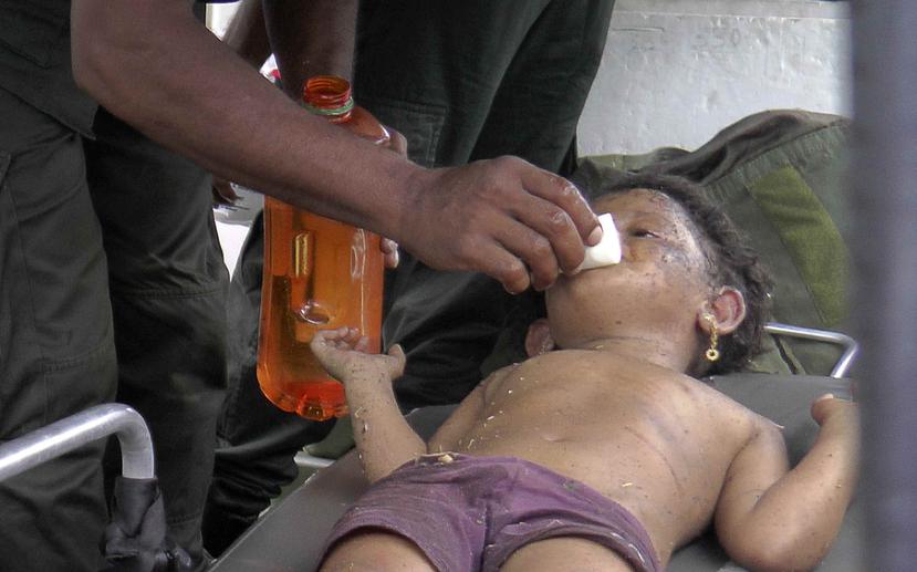 Un soldado limpia la cara de una niña luego de que la menor fuera encontrada en el lugar de la explosión y el tiroteo el sábado. (AP/ Achala Upendra)