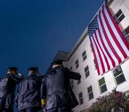 Socorristas saludan bajo una lluvia torrencial mientras se despliega una bandera de Estados Unidos en el Pentágono en Washington, al amanecer del 21 aniversario de los ataques terroristas del 11 de septiembre.
