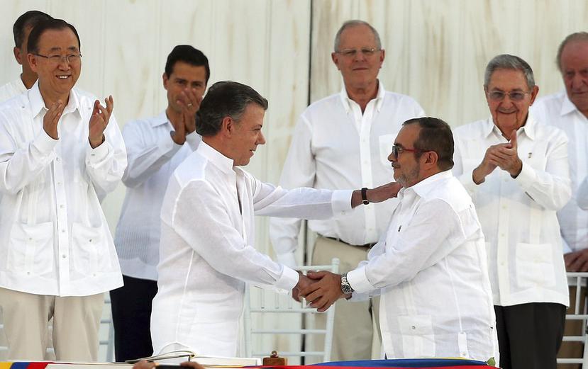 El presidente de Colombia, Juan Manuel Santos, y el máximo comandante las FARC, Rodrigo Londoño, se estrechan las manos después de firmar el Acuerdo de paz. (AP).