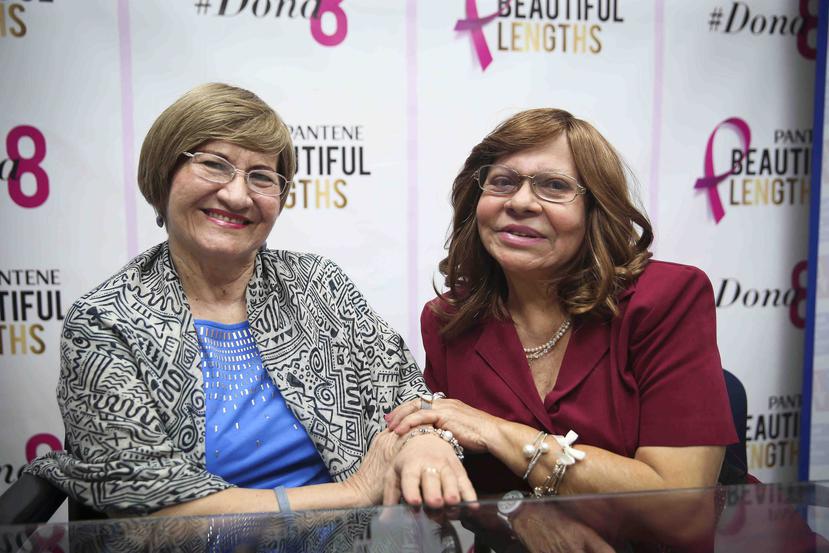 Unas sonrientes Ivette Giusti Bravo y Daría Angarita muestras sus pelucas.