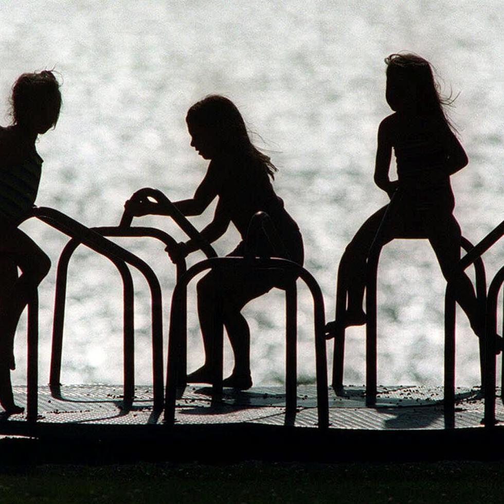 A group of young girls playing on a playground merry-go-round Monday, Aug. 7, 2000, are silhouetted on High Cliff Beach at High Cliff State Park, in Sherwood, Wis. (AP Photo/The Post-Crescent, Dan Powers) TEMAS PARQUE MECEDORA PLAYGROUND COLUMPIO