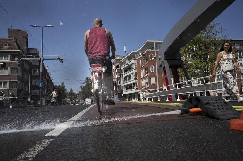 En medio del calor intenso, trabajadores municipales de Ámsterdam echan agua en los puentes sobre los canales para impedir la expansión del metal, que los trabaría y bloquearía el tránsito fluvial.