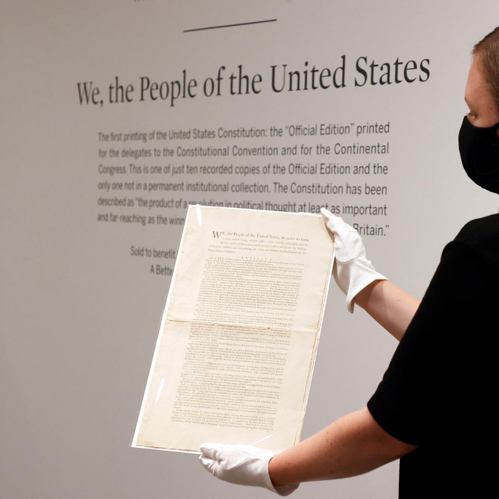 Un especialista en libros y manuscritos de Sotheby's sostiene una copia impresa de la Constitución de los Estados Unidos de 1787 durante un avance de una próxima subasta en Sotheby's, Nueva York, el 17 septiembre de 2021.