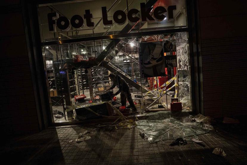Un trabajador inspecciona una tienda destruida durante las manifestaciones en Barcelona. (AP)