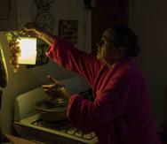 Marta Bermúdez Robles, de 66 años, cuelga una lámpara en su cocina, en Adjuntas, Puerto Rico, ante la falta de electricidad desde el paso de los huracanes Irma y María. (AP)