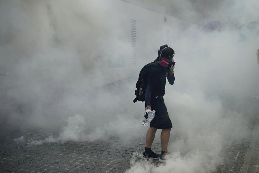 Un manifestante contrario al gobierno camina entre el gas lacrimógeno, en medio de choques con la policía en la zona de Wong Tai Sin en Hong Kong. (AP Foto/Felipe Dana)