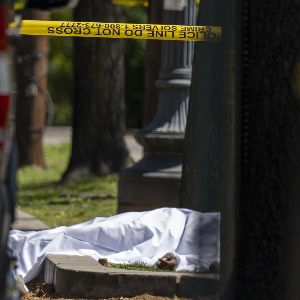 Una víctima bajo una sábana mientras agentes del Departamento de Policía Metropolitana investigan la escena de un tiroteo frente a la funeraria Stewart, el martes 11 de abril de 2023, en Washington D.C.