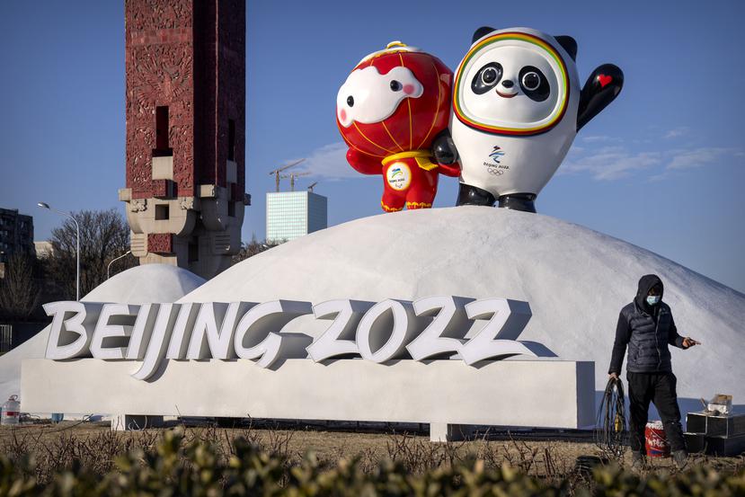 Un empleado camina frente a las mascotas de los Juegos Olímpicos y Paraolímpicos de Invierno de Pekín.