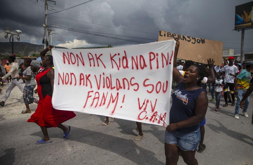 Haitianos protestan con una pancarta que dice en creole "No a los secuestros, no a la violencia contra las mujeres. Viva Christian Aid Ministries".