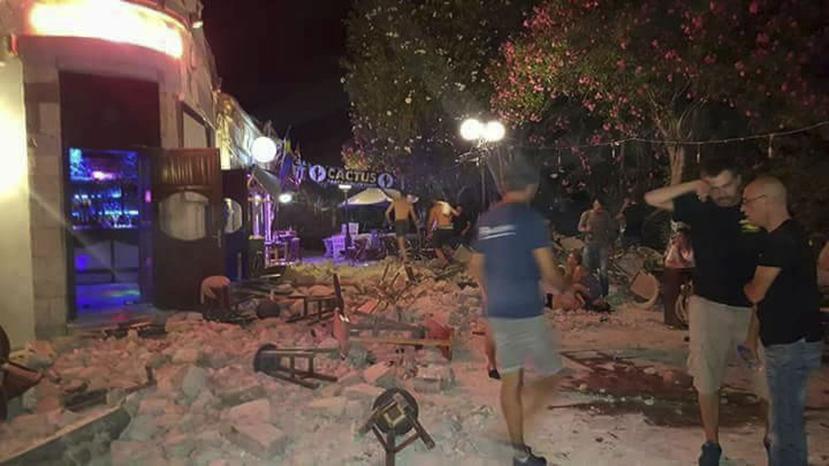 Un hombre yace en el piso mientras otros turistas permanecen afuera de un bar después de un terremoto en la isla griega de Kos. (AP)