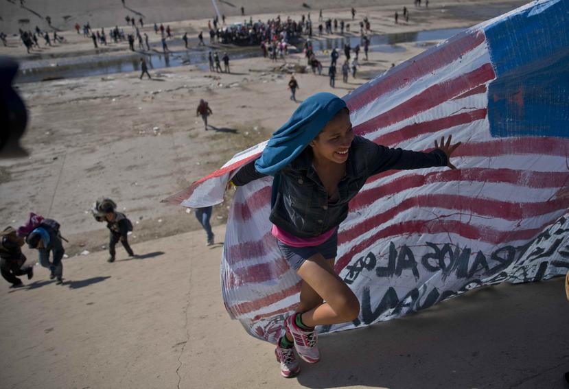 Un grupo de migrantes cruza el lecho de un río en la frontera con Estados Unidos tras superar a unos policías mexicanos en Tijuana. (AP)