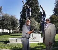 En esta foto del 17 de octubre de 2018, John Carlos (izquierda) y Tommie Smith posan frente a la estatua que los muestra con el puño en alto, la señal de protesta que hicieron en el podio de los Juegos Olímpicos de México 1968. La estatua se encuentra en el campus de la Universidad Estatal de San José, en California.