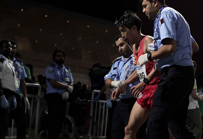 Médicos asisten al chino Shaohui Yang tras completar el maratón del Mundial de atletismo en Doha. (AP)