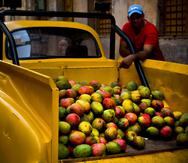 Un vendedor de mangos espera por clientes al lado de su Chevrolet clásico que  convirtió en camioneta, en La Habana, Cuba.