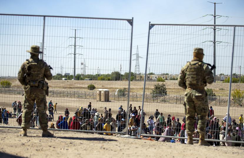 Imagen de archivo de gran cantidad de migrantes junto a la verja fronteriza para entrar en El Paso, Texas, ante la mirada de miembros de la Guardia Nacional del estado.
