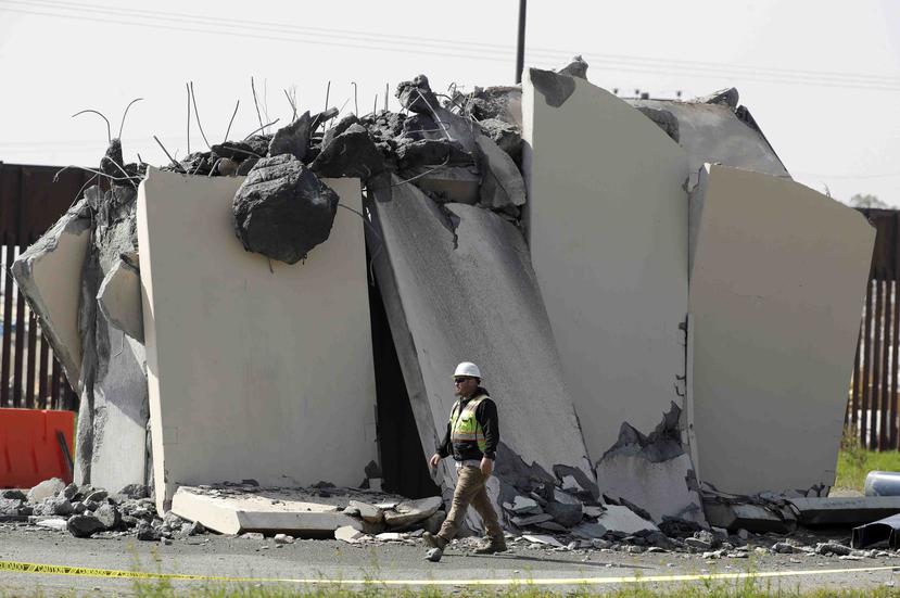 Un trabajador camina cerca de un muro prototipo destruido en la frontera con Tijuana. (AP)