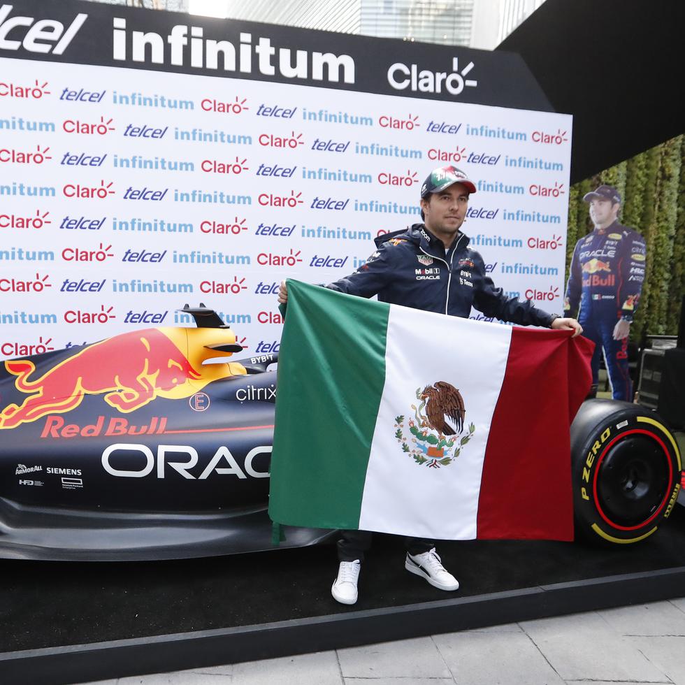 El piloto mexicano de la Fórmula Uno, Sergio 'Checo' Pérez, de Red Bull Racing, posa con la bandera durante una reciente conferencia de prensa en la Ciudad de México.