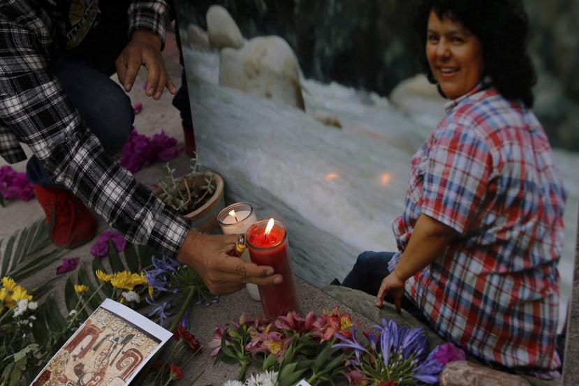 Un hombre coloca una vela encendida junto a una imagen de la activista ambiental y de derechos indígenas Berta Cáceres en una ceremonia espiritual, un día antes de un juicio contra uno de los presuntos autores intelectuales del asesinato de Cáceres, en Tegucigalpa, Honduras, el lunes 5 de abril de 2021.