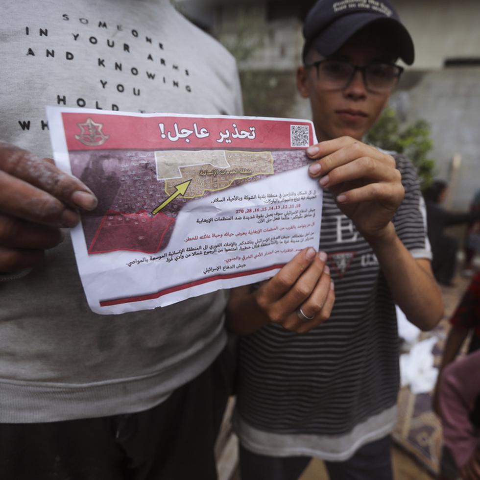 Palestinos sostienen folletos arrojados por aviones israelíes que les dicen que evacúen antes de una operación militar israelí en Rafah, en el sur de la Franja de Gaza.