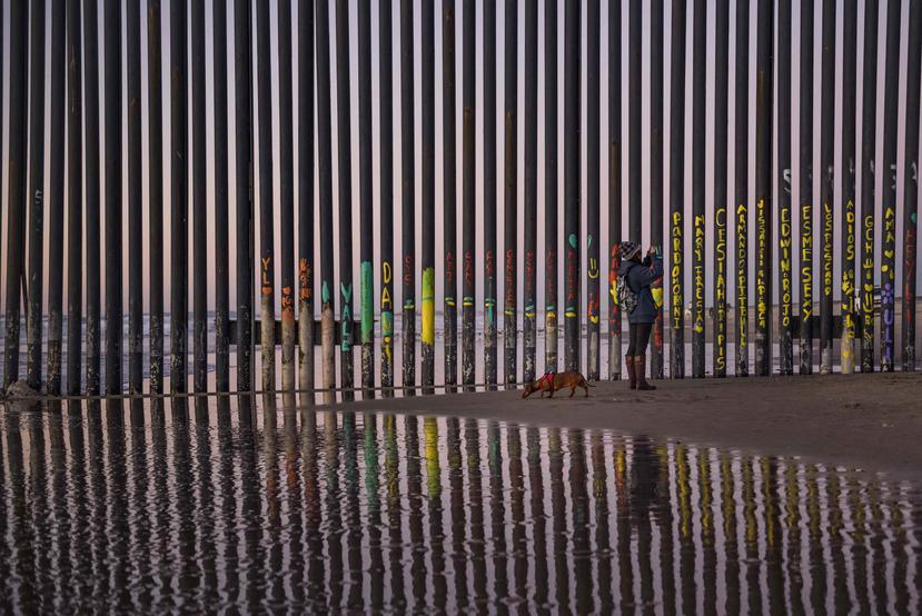 Una mujer toma una foto junto a la barda fronteriza entre San Diego, California, y Tijuana, vista desde México. (AP)