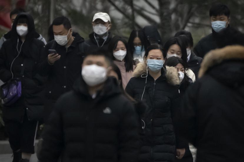 Transeúntes con mascarilla caminan por una calle de un distrito empresaria en el centro de Beijing, China, el 12 de enero de 2023.
