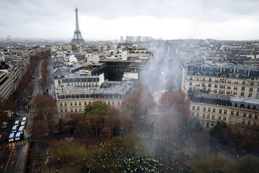 Manifestantes vestidos con chalecos amarillos se enfrentan a los cañones de agua de la policía durante una protesta cerca de la avenida de los Campos Elíseos, en París, el 1 de diciembre de 2018. (AP /Kamil Zihnioglu)