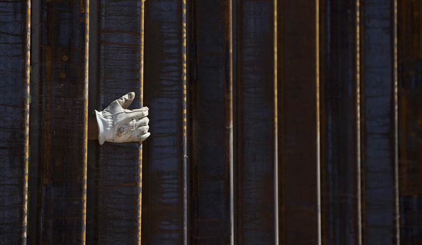 La mano de un albañil se asoma por una parte del muro fronterizo en construcción en Lukeville, Arizona. (Mamta Popat/Arizona Daily Star vía AP)