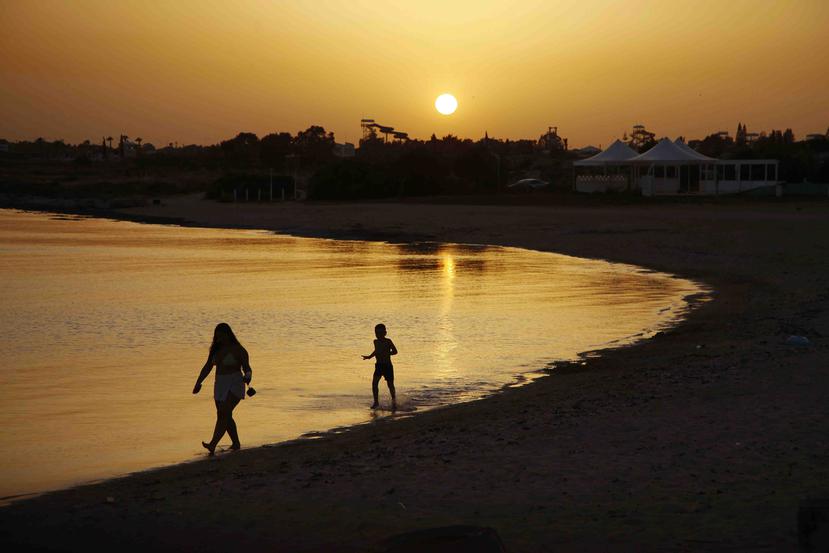 Dos personas caminan en la playa en una franja vacía de la playa Dome en Makrinissos, en el destino turístico Ayia Napa en Chipre. (AP Foto/Petros Karadjias, Archivo)