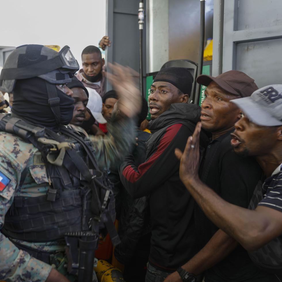 Agentes de la policía tratan de controlar a una multitud que intenta obtener combustible en una gasolinera de Puerto Príncipe, Haití.
