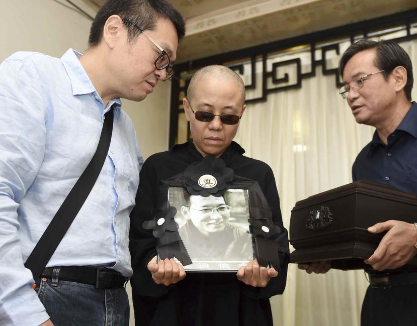 La esposa del fallecido disidente y Premio Nobel de la Paz Liu Xiaobo, sostiene un retrato suyo durante su funeral, en una funeraria en Shenyang. (AP)