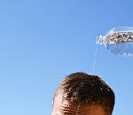 Imagen de archivo de un hombre que se echa agua por encima de la cabeza ante la alta sensación de calor.