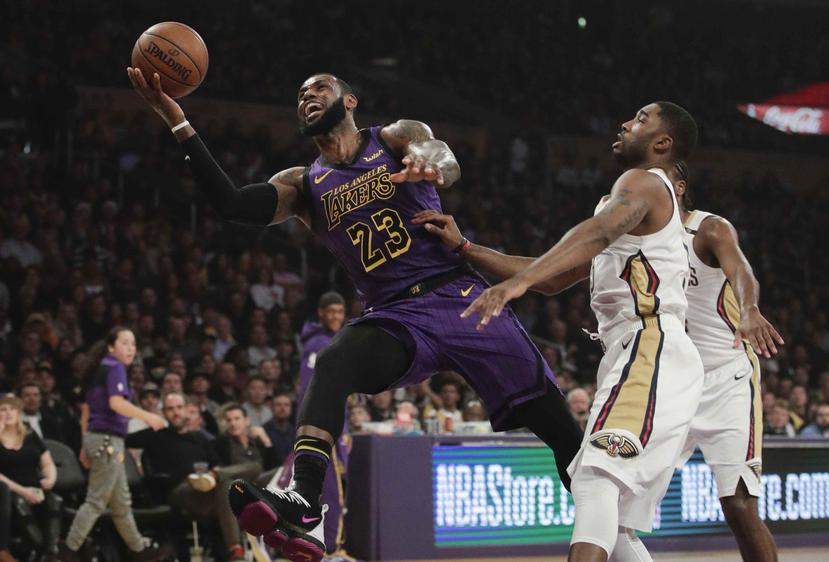 LeBron James, izquierda, de los Lakers de Los Ángeles, salta hacia la canasta enfrente de E'Twaun Moore, de los Pelicans de Nueva Orleáns, durante un partido de la NBA el viernes 21 de diciembre del 2018 en Los Ángeles. (AP/Jae C. Hong)