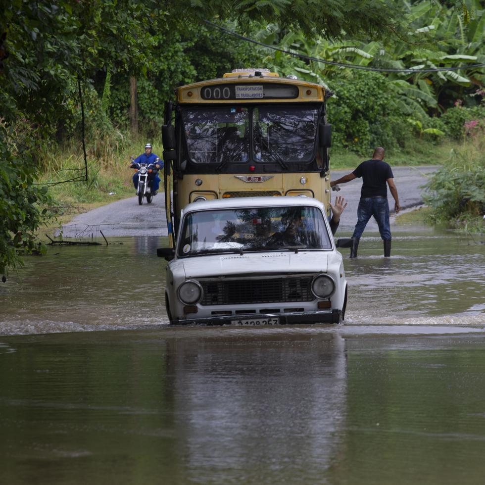 Vehículos tratan de avanzar por una vía inundada por lluvias torrenciales, en La Habana, luego que el quinto frente de frío de la temporada azotara la capital cubana.