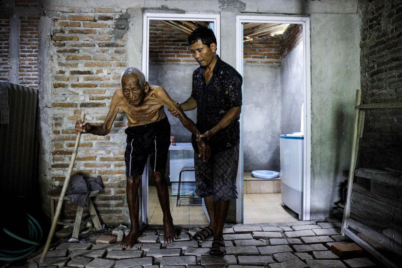 El hombre de 146 años, conocido como Mbah Gotho, caminando junto a su nieto Suryanto, de 47 años. (Agencia EFE)