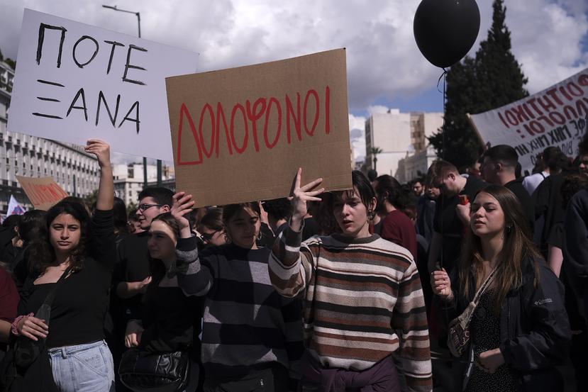 Varias personas sostienen pancartas que dicen "Asesinos" y "Nunca más", durante una protesta frente al Parlamento griego por el reciente choque de dos trenes.