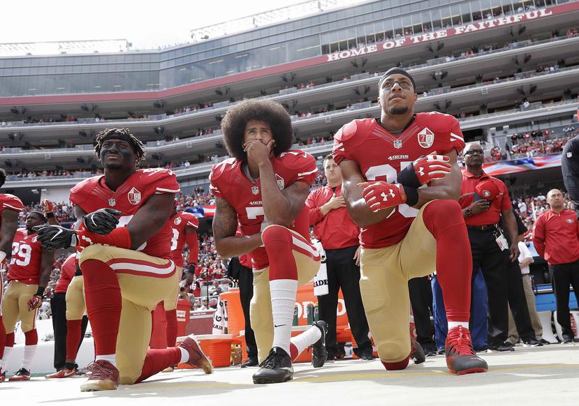Colin Kaepernick (centro), de los 49ers de San Francisco, se arrodilla con otros compañeros durante la interpretación del himno nacional. (AP)