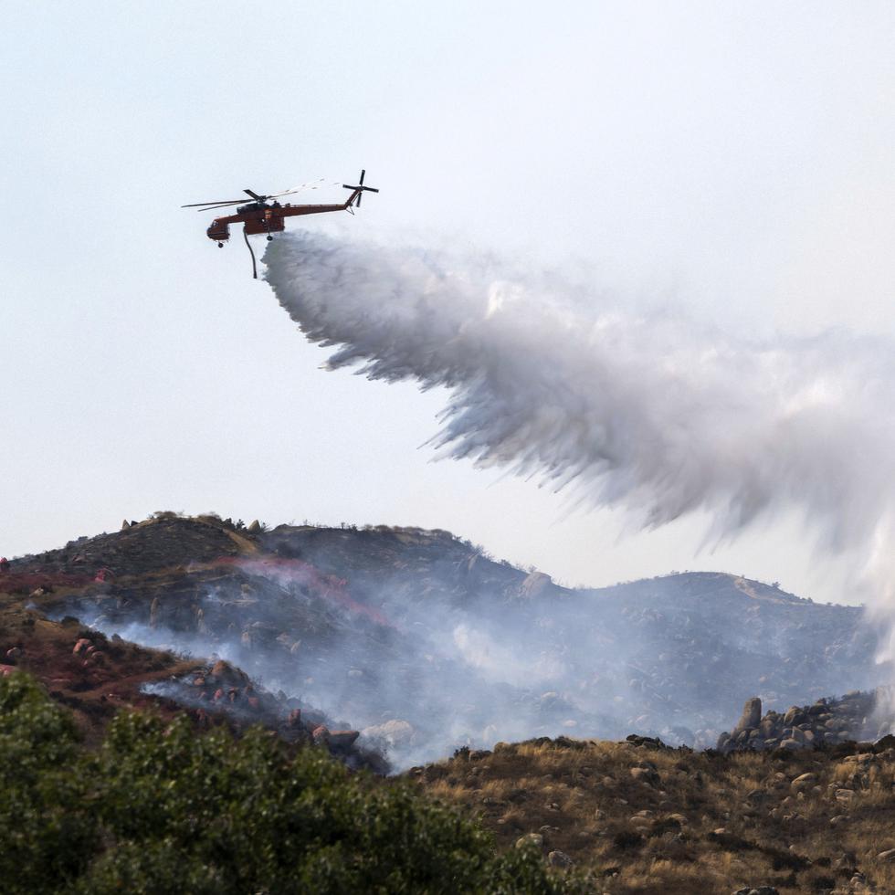 Un helicóptero trata de apagar un incendio en Reche Canyon cerca de Moreno Valley, California, el 14 de julio de 2023.