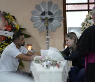 Los padres de la niña Larissa Maia Toldo, de siete años, quien fue asesinada por un hombre con un hacha dentro de una guardería, se sientan junto al ataúd que contiene sus restos durante un velorio en el cementerio de São José, en Blumenau, Brasil, el jueves 6 de abril de 2023. (AP Foto/André Penner)