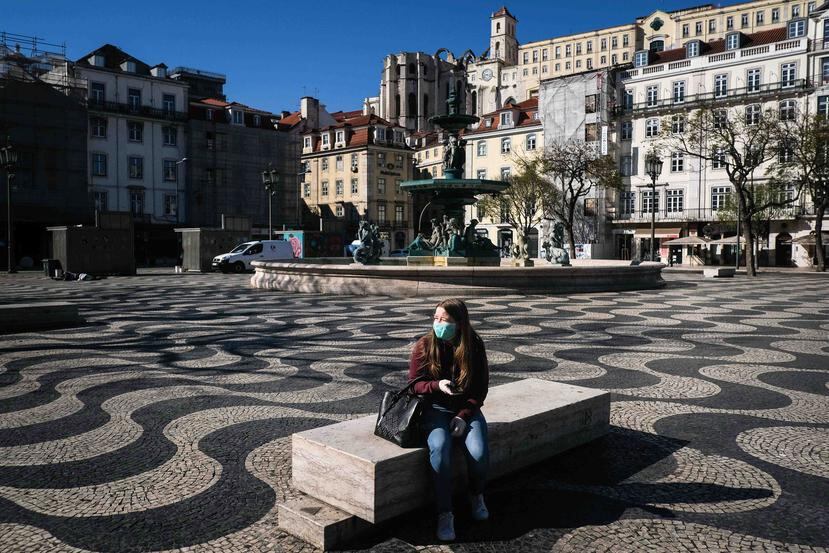 Una mujer con mascarilla está sentada en una desértica plaza en la ciudad de Lisboa. (EFE)