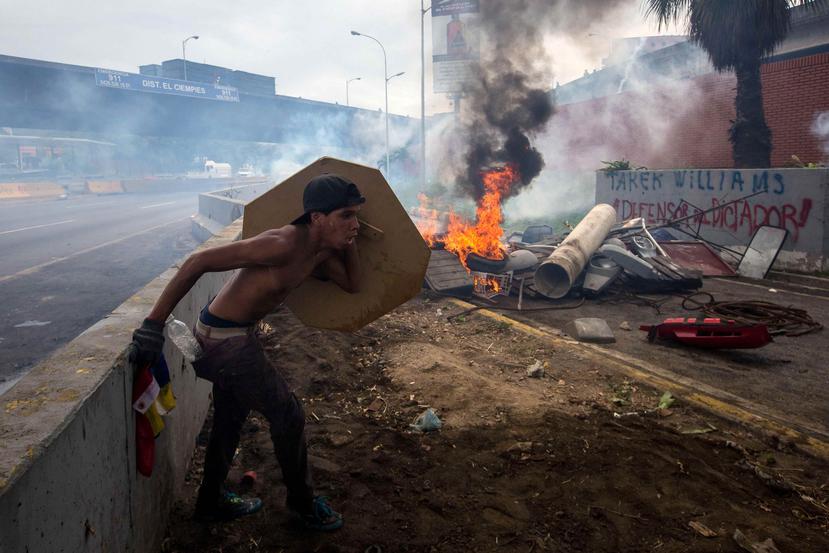 Un manifestante se protege durante una confrontación con miembros de la Guardia Bolivariana. (EFE)