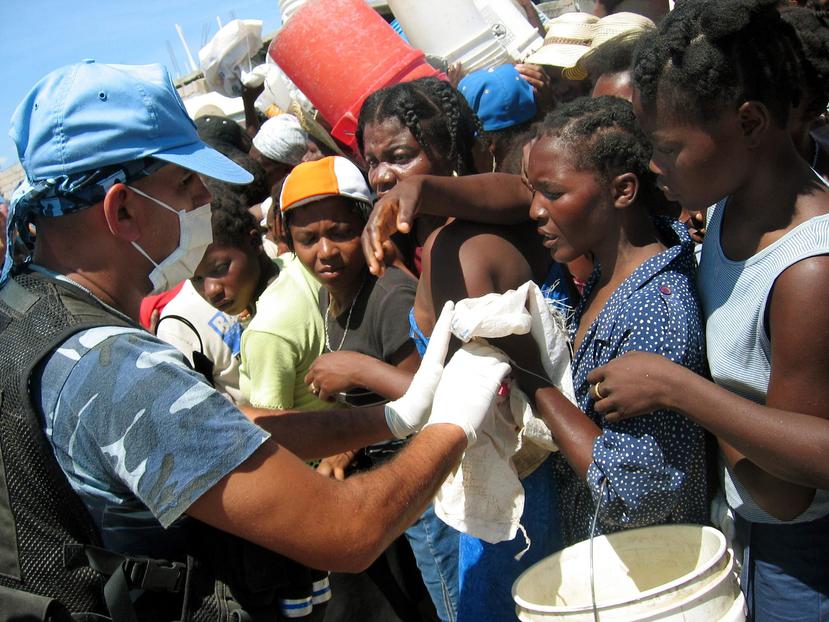 Un trabajador humanitario asiste a un grupo de personas en Haití. (EFE)
